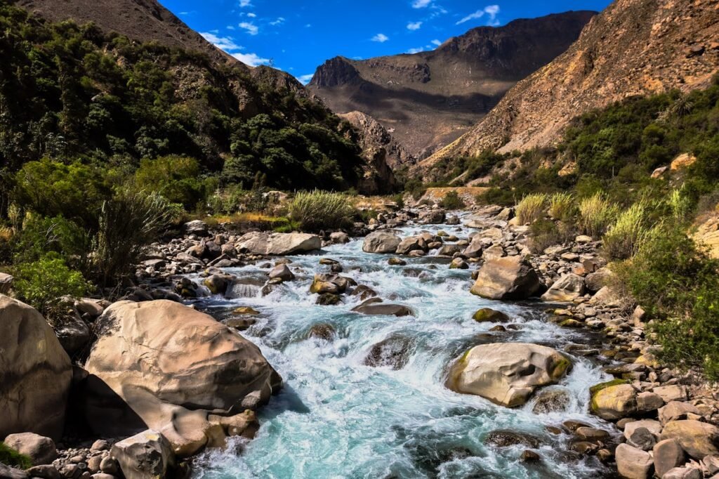 A picturesque mountain river flowing through a rugged landscape with lush greenery and rocky terrain.